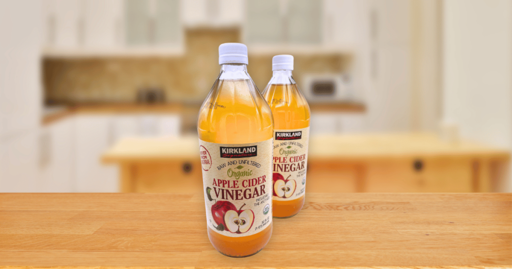 Two bottles of organic apple cider vinegar on a wooden counter.