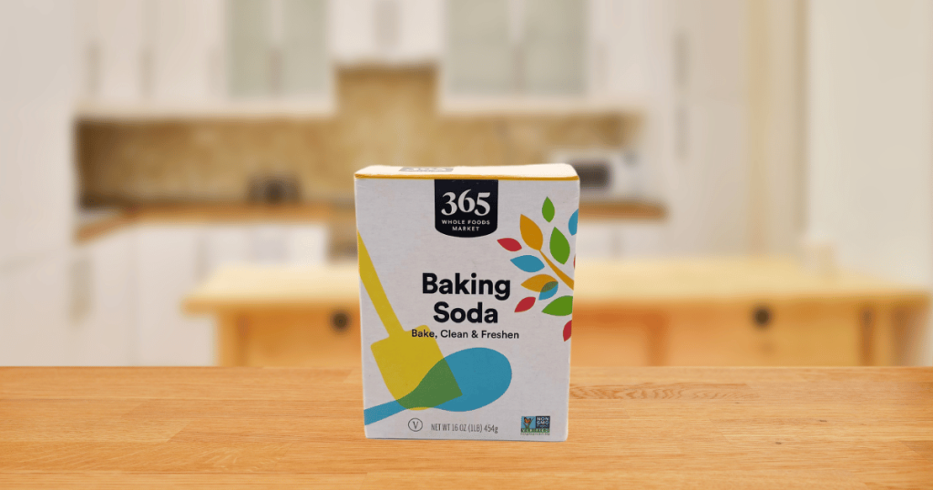 Small white box of baking soda on a wooden counter.